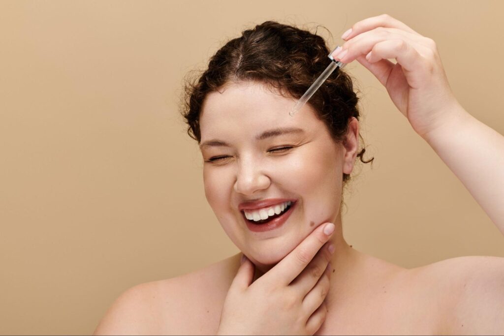 Joyful woman applying energizing serum for radiant, glowing skin.