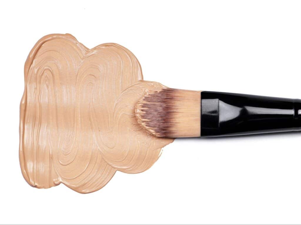 Makeup brush smoothing liquid foundation for a flawless finish.