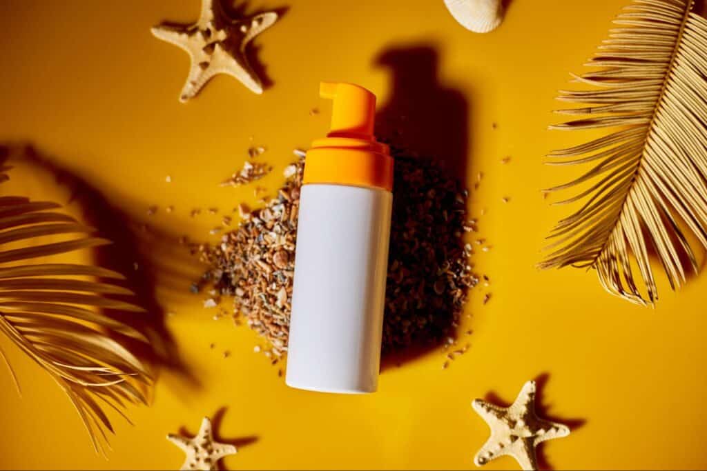 Sunscreen bottle surrounded by beach elements for sun protection.