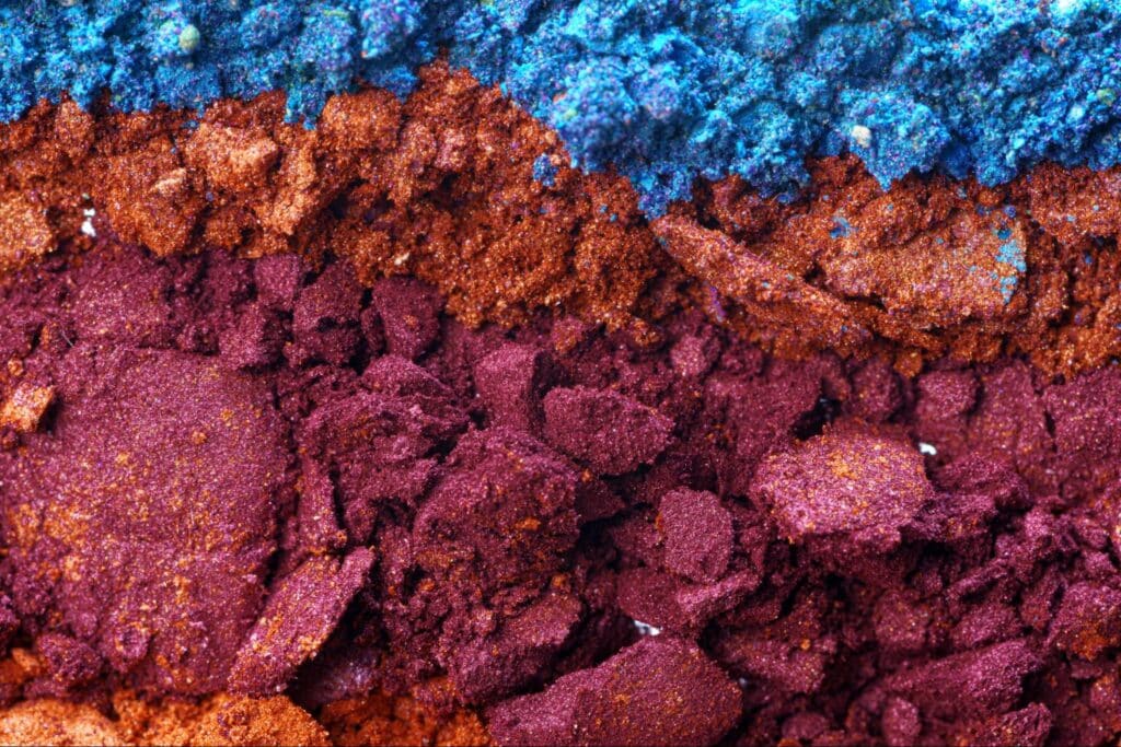 Vibrant layers of mineral powders in blue, red, and purple hues.