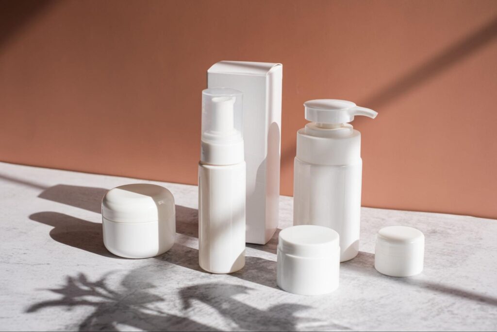 Minimalist white skincare products on a marble surface with a warm backdrop.