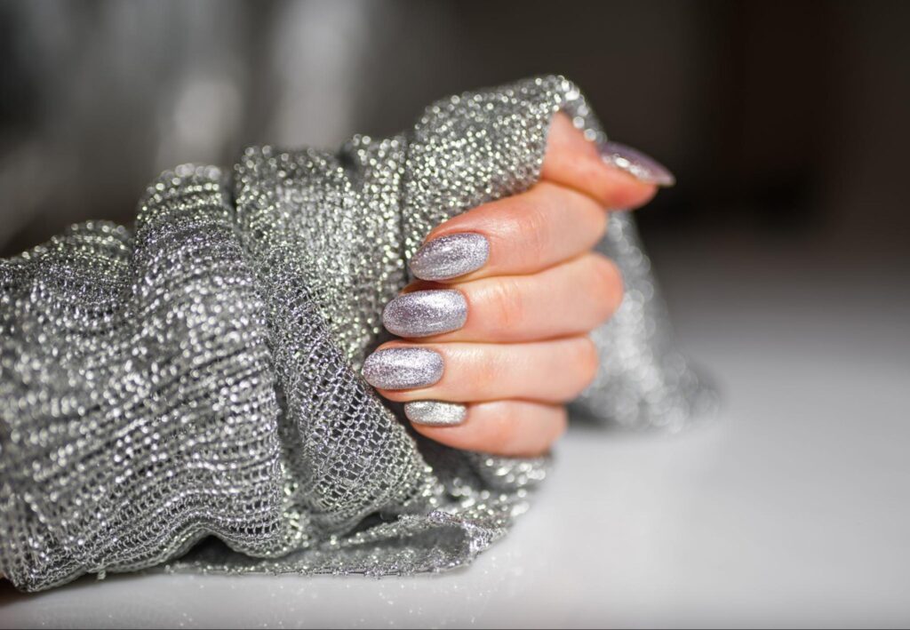 Sparkly silver nails paired with a cozy, shimmering sweater for a stylish look.