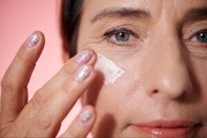 Woman applying moisturizer for a radiant and youthful complexion.