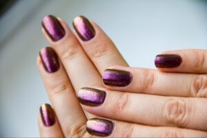 Elegant purple and gold ombre nails with a shimmering finish.