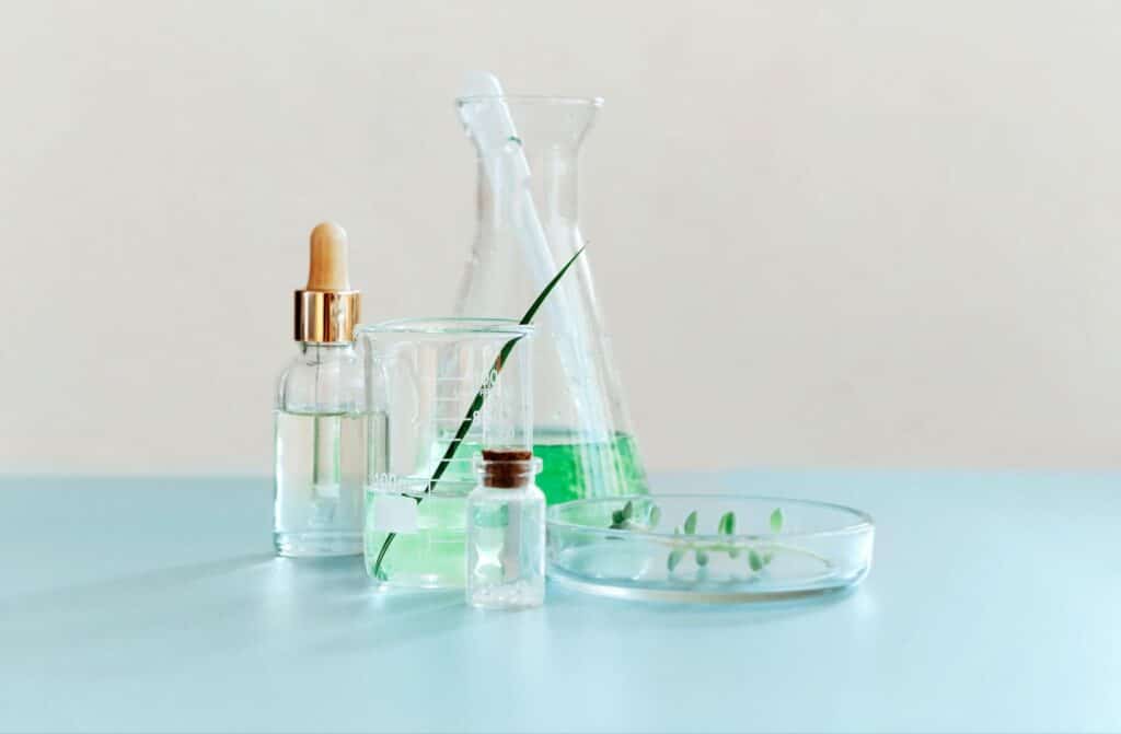 Natural skincare ingredients in glass containers on a blue surface with plants.