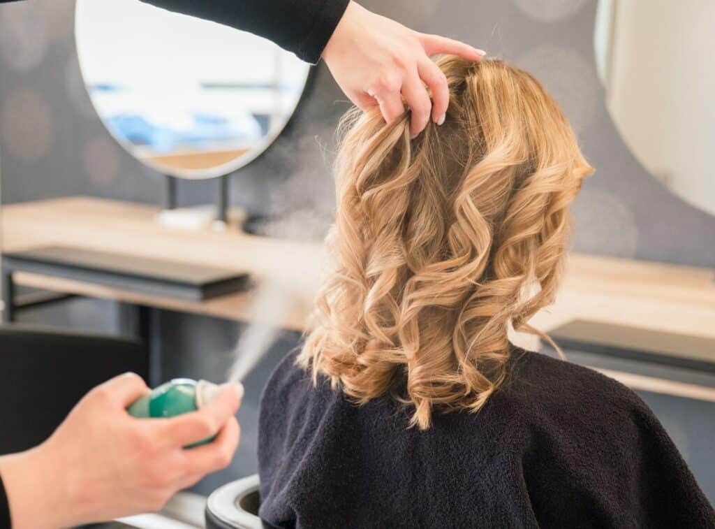 Stylist creating beautiful curls with spray for a perfect salon finish.